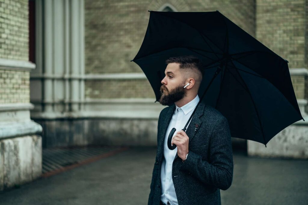 Geschäftsmann hält einen schwarzen Regenschirm