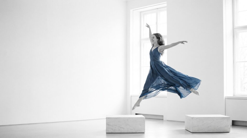 Dancer in a blue dress leaping across the gap between two white platforms