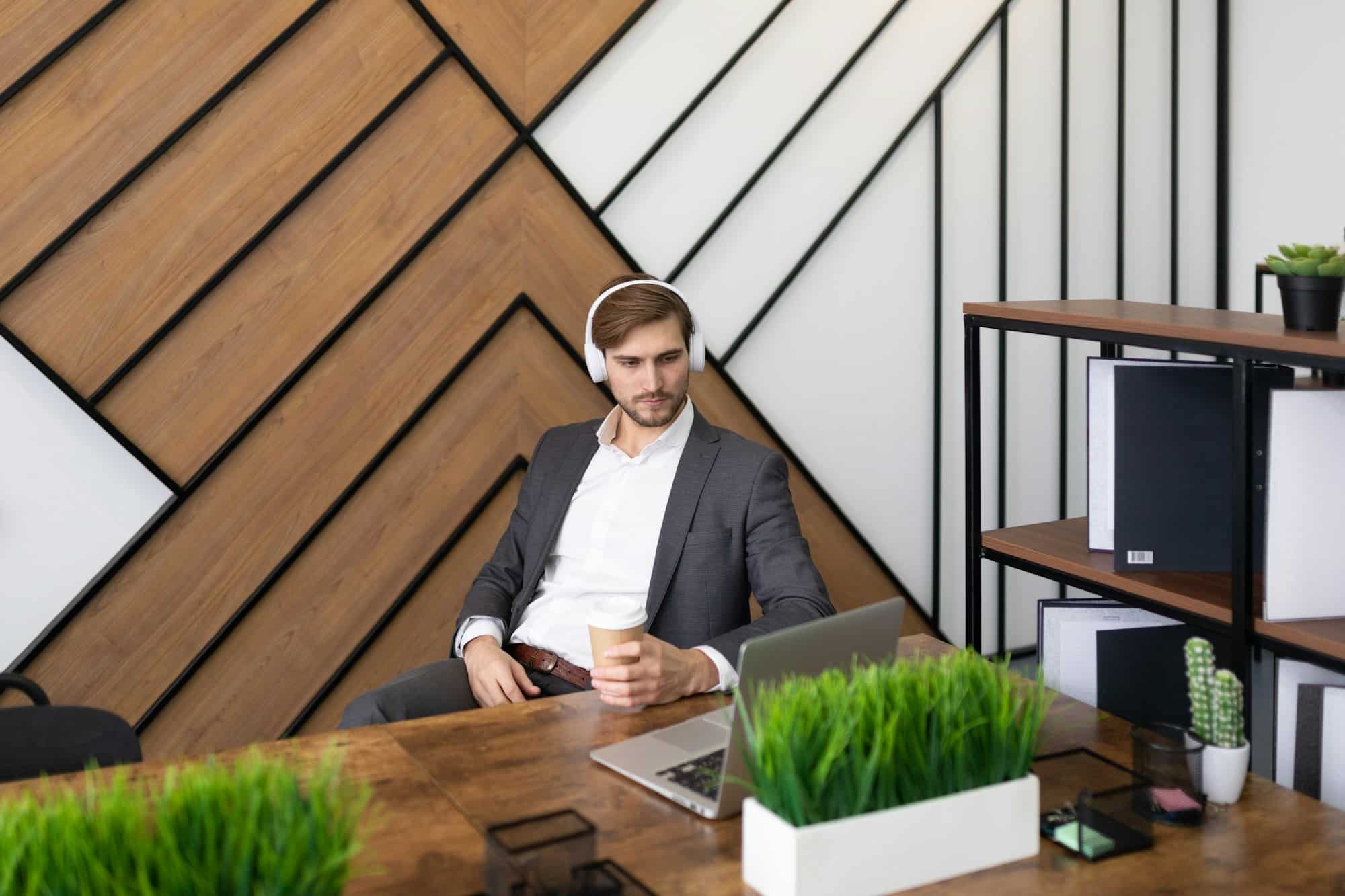 a man in an office wearing headphones listening to a training webinar