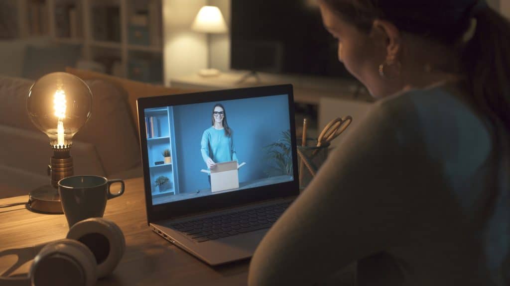 Femme regardant un youtuber ouvrir une boîte de livraison