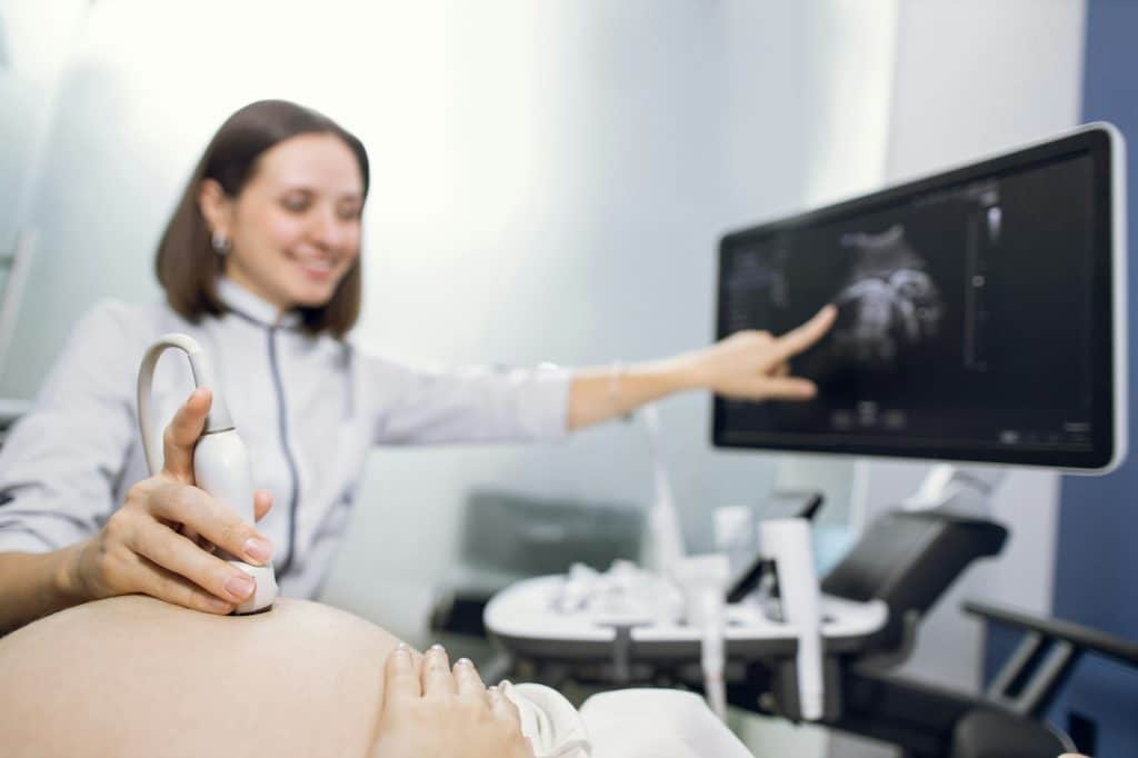 Cropped shot of a pregnant woman during ultrasound scanning at the fertility clinic.