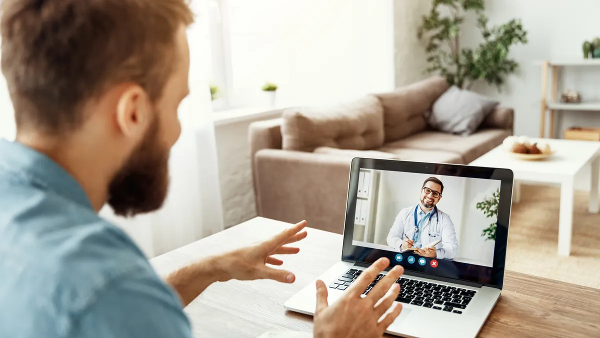 Man video chatting with doctor on laptop.