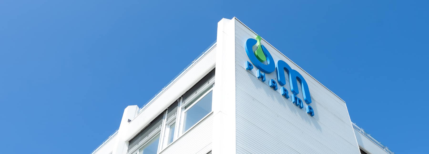 Pharmaceutical company building with logo on facade.