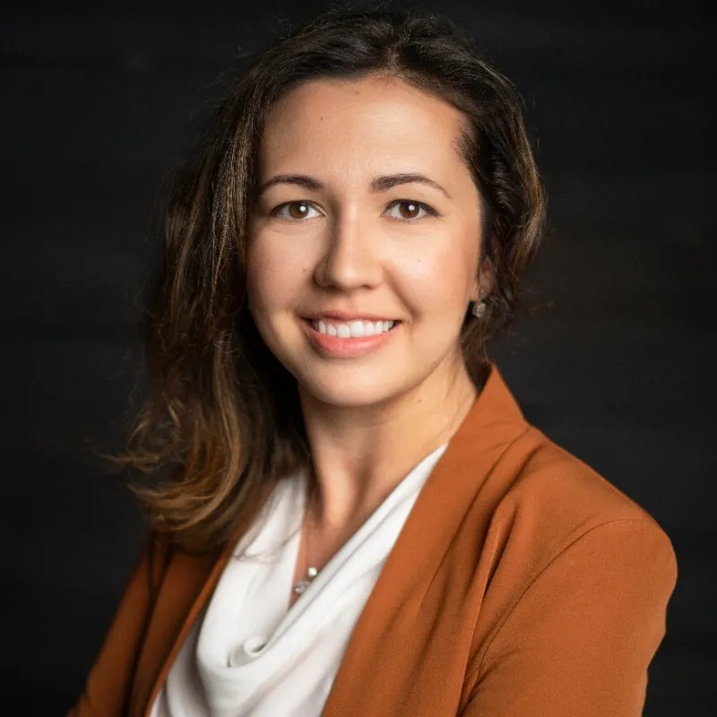 Portrait d'une femme souriante en tenue professionnelle.