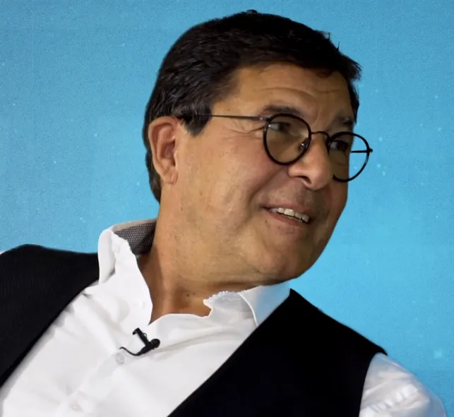 Lächelnder Mann mit Brille auf blauem Hintergrund.